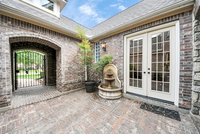 property entrance with brick siding, a gate, and french doors