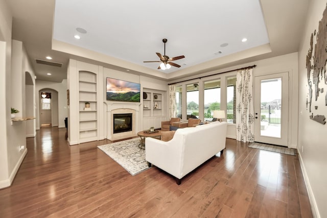 living area featuring dark wood-style flooring, baseboards, and a raised ceiling