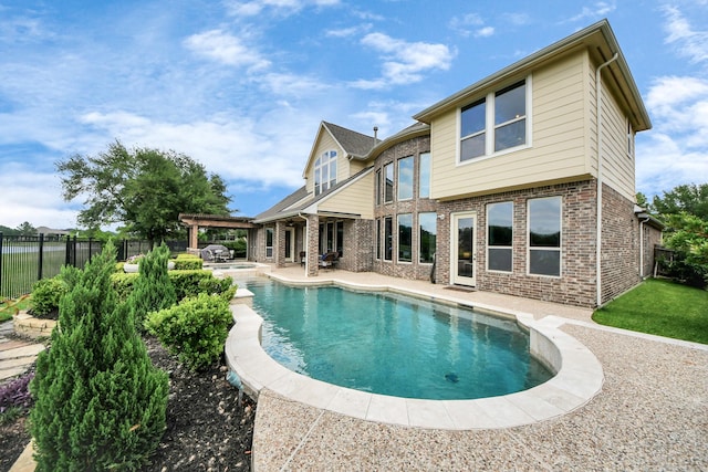 rear view of house featuring a fenced in pool, a fenced backyard, brick siding, and a patio