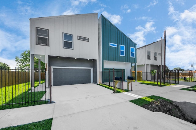 contemporary house featuring a garage, board and batten siding, fence private yard, and driveway