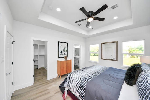 bedroom featuring light wood-style flooring, visible vents, a tray ceiling, baseboards, and recessed lighting