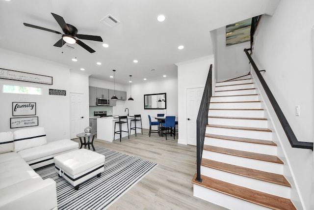 living room featuring recessed lighting, light wood-style floors, stairs, visible vents, and a ceiling fan