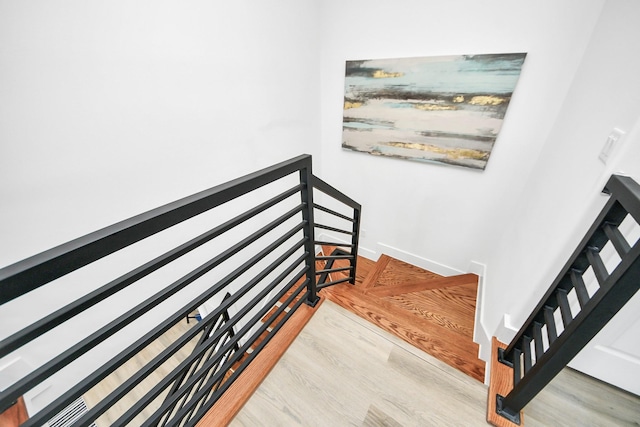stairs featuring radiator heating unit, wood finished floors, and baseboards