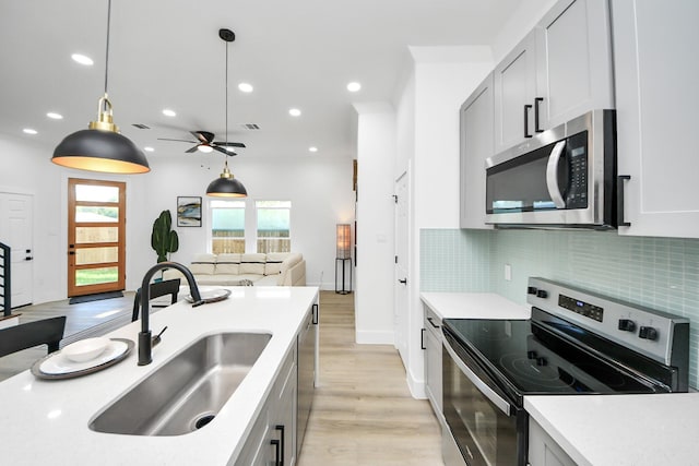 kitchen featuring light countertops, stainless steel appliances, light wood-type flooring, and a sink