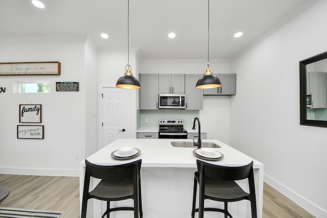 kitchen featuring a sink, appliances with stainless steel finishes, gray cabinetry, light countertops, and baseboards
