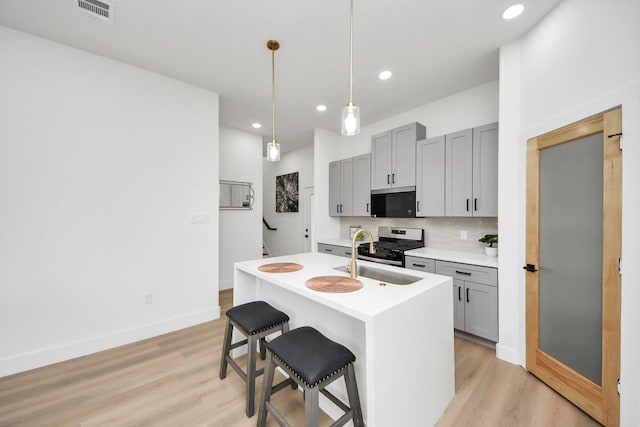 kitchen featuring a sink, gray cabinetry, visible vents, and stainless steel gas range