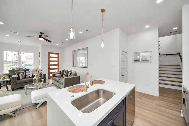 kitchen featuring light wood finished floors, a sink, ceiling fan, visible vents, and open floor plan