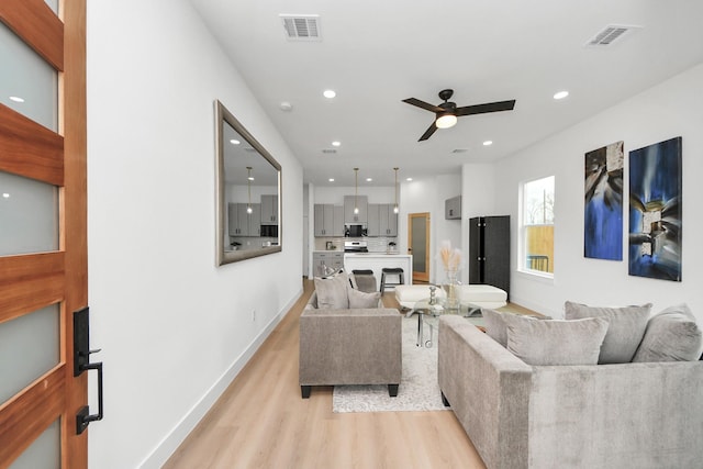 living area featuring visible vents, ceiling fan, light wood finished floors, and recessed lighting