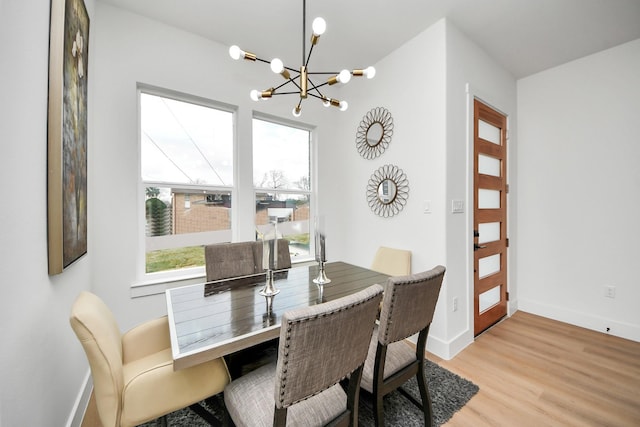 dining space with baseboards, an inviting chandelier, and light wood finished floors