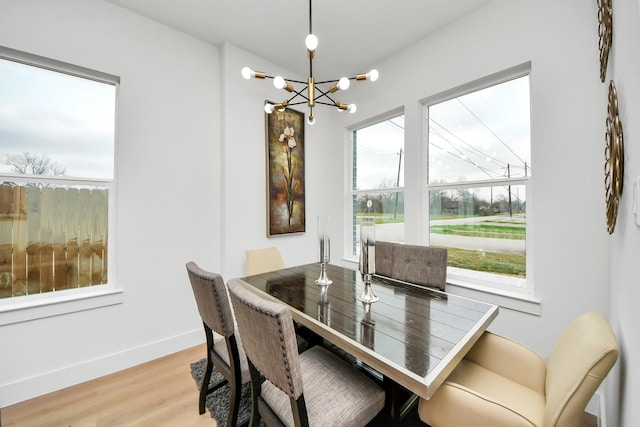 dining area featuring an inviting chandelier, baseboards, wood finished floors, and plenty of natural light