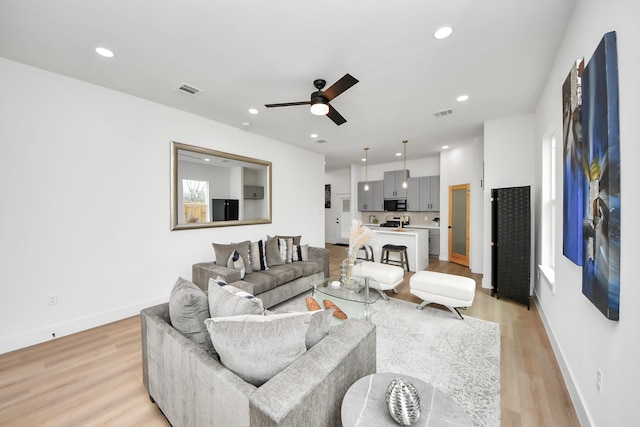 living room with recessed lighting, light wood-type flooring, a ceiling fan, visible vents, and baseboards