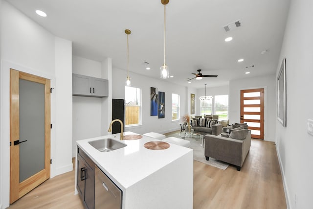 kitchen with a sink, baseboards, light wood-style floors, and visible vents