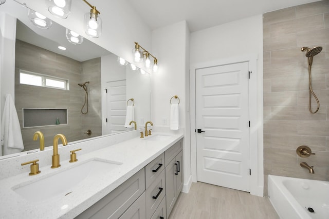 bathroom featuring tiled shower / bath combo, a sink, double vanity, and wood finished floors