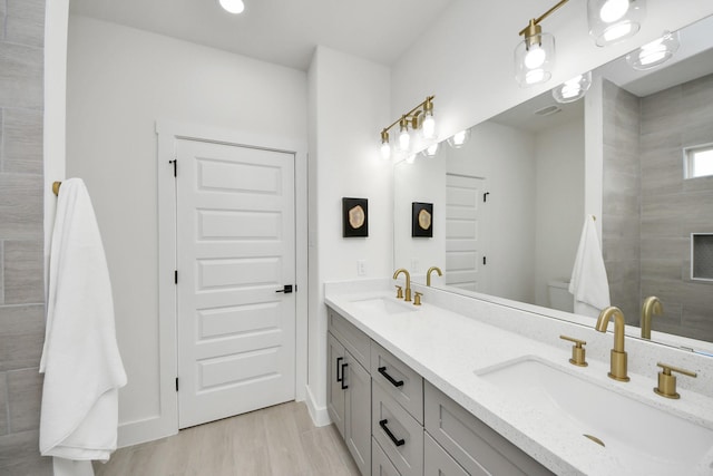 full bathroom featuring toilet, double vanity, a sink, and wood finished floors