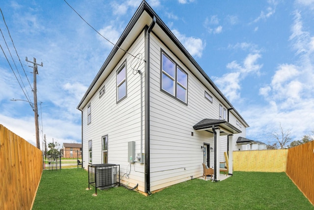 rear view of property with a yard, a fenced backyard, and central AC unit