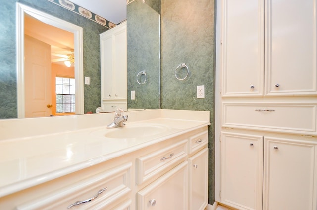 bathroom featuring vanity, a ceiling fan, and wallpapered walls