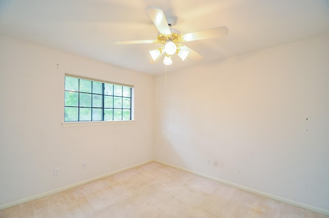 empty room featuring light colored carpet, a ceiling fan, and baseboards
