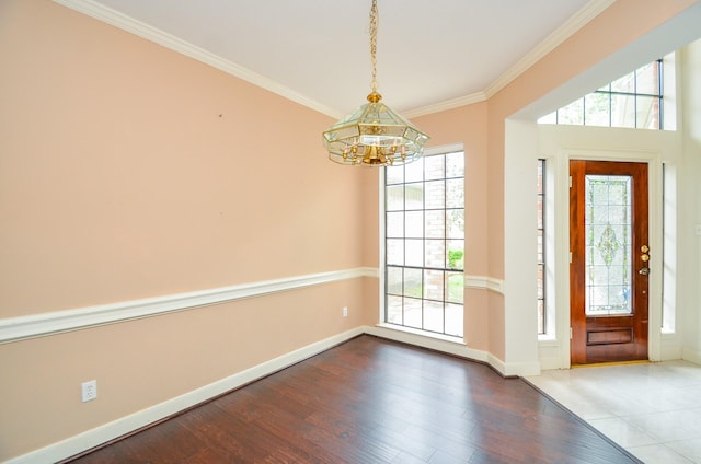 interior space with baseboards, wood finished floors, an inviting chandelier, and ornamental molding