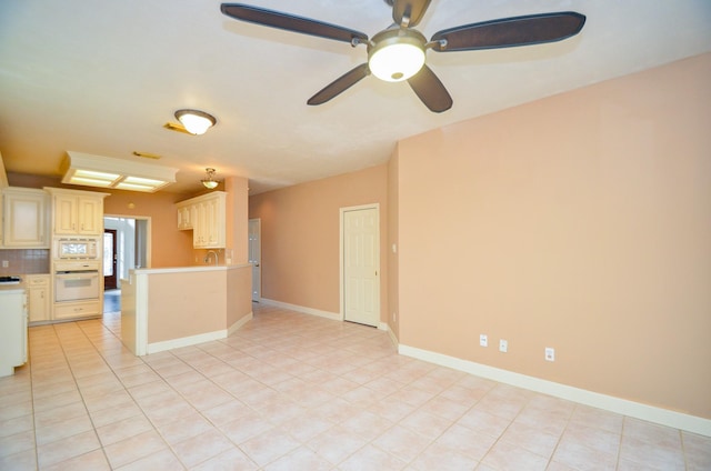 unfurnished living room featuring light tile patterned floors, a sink, ceiling fan, and baseboards