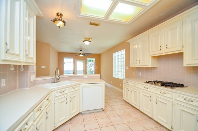 kitchen featuring light tile patterned floors, a sink, dishwasher, a peninsula, and stainless steel gas cooktop