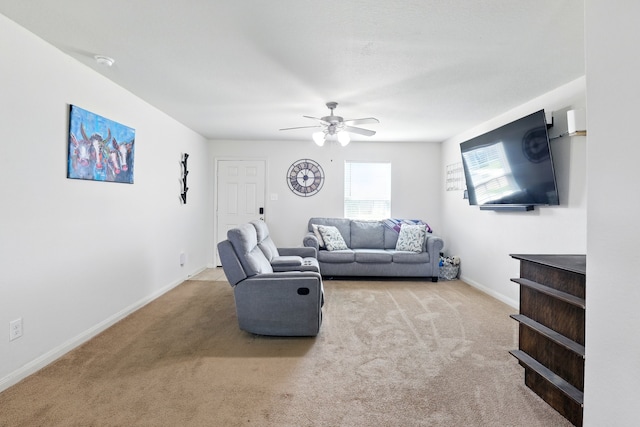 carpeted living area with ceiling fan and baseboards