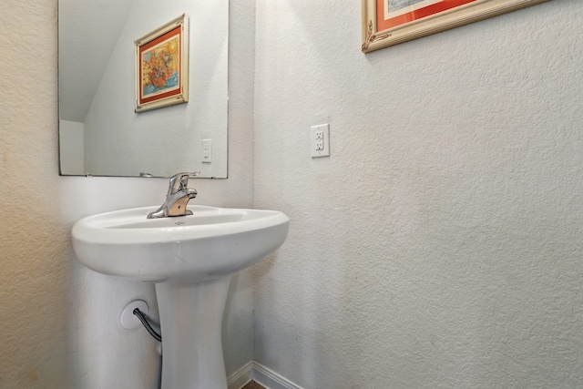 bathroom with a textured wall and a sink