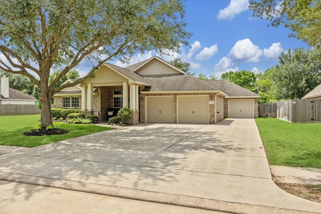 view of front of property with concrete driveway, an attached garage, fence, brick siding, and a front lawn