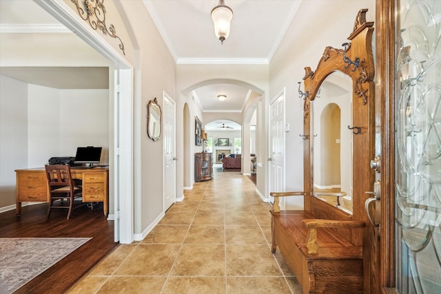 hallway featuring ornamental molding, arched walkways, and baseboards