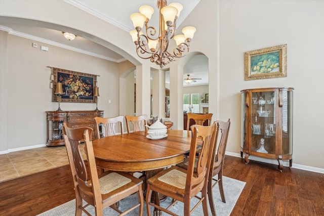 dining area featuring hardwood / wood-style floors, baseboards, arched walkways, and ornamental molding