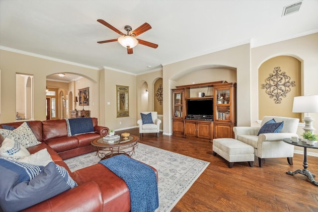 living area with dark wood finished floors, arched walkways, ceiling fan, visible vents, and crown molding
