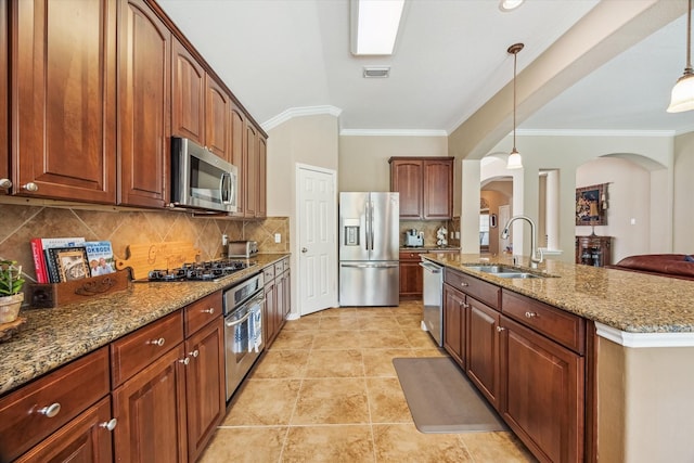 kitchen featuring arched walkways, decorative backsplash, appliances with stainless steel finishes, stone counters, and a sink