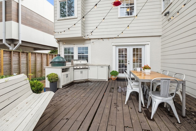 wooden deck with outdoor dining area, exterior kitchen, french doors, and area for grilling