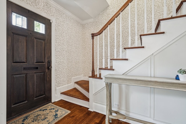 foyer with crown molding, wood finished floors, stairway, and wallpapered walls