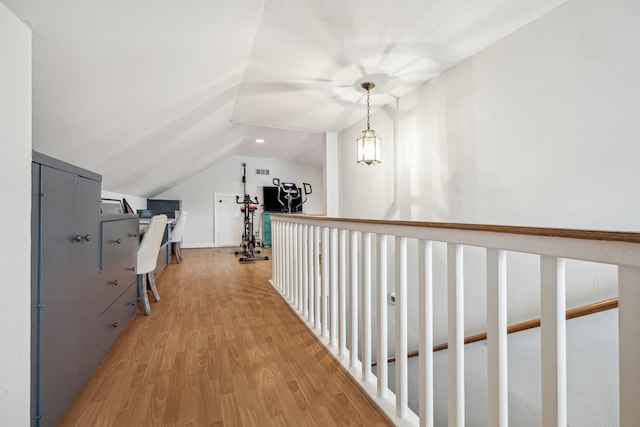 hallway featuring visible vents, light wood finished floors, and lofted ceiling