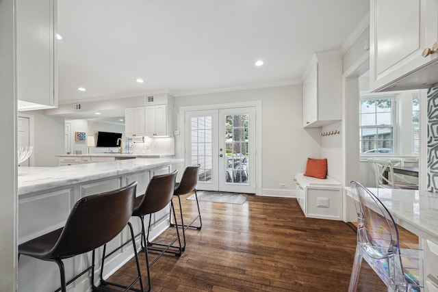 kitchen featuring crown molding, a breakfast bar area, french doors, white cabinetry, and dark wood-style floors