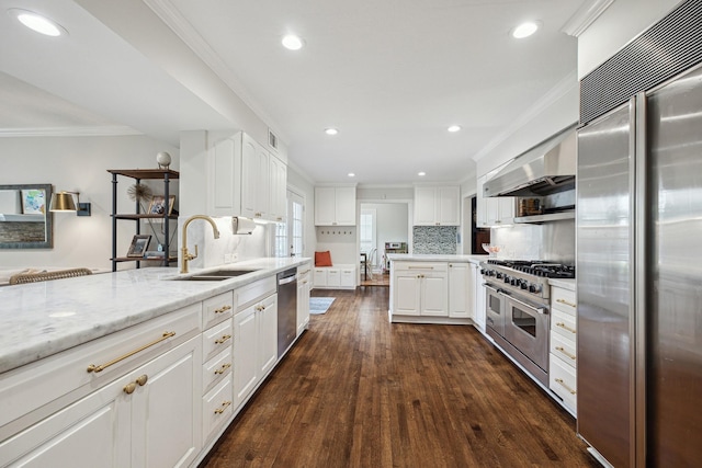 kitchen featuring a peninsula, high quality appliances, ventilation hood, a sink, and dark wood finished floors