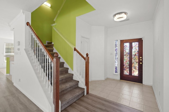 foyer with a wealth of natural light, crown molding, and stairway