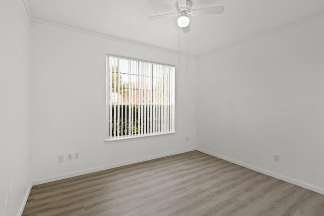 spare room featuring wood finished floors, a ceiling fan, ornamental molding, and baseboards