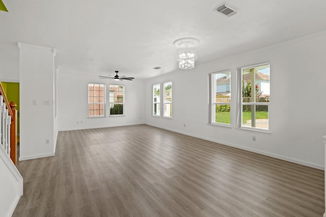 unfurnished living room featuring stairway, visible vents, baseboards, wood finished floors, and ceiling fan with notable chandelier