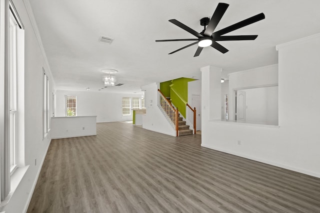 unfurnished living room featuring wood finished floors, stairway, ceiling fan with notable chandelier, baseboards, and visible vents