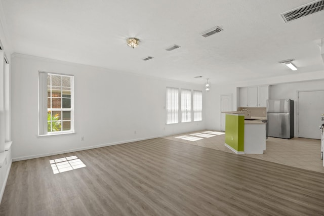 unfurnished living room featuring visible vents and plenty of natural light