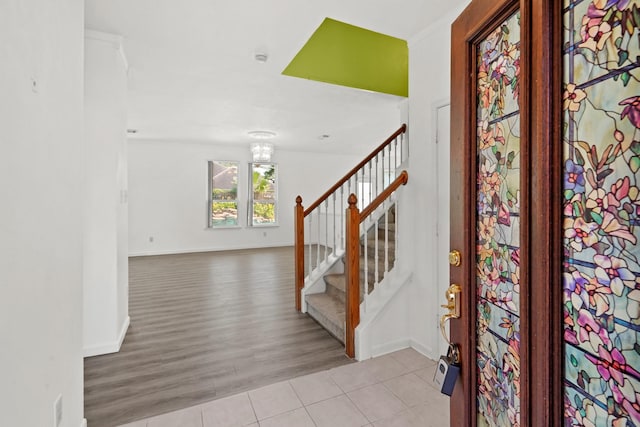 entrance foyer featuring tile patterned floors, baseboards, a notable chandelier, and stairs