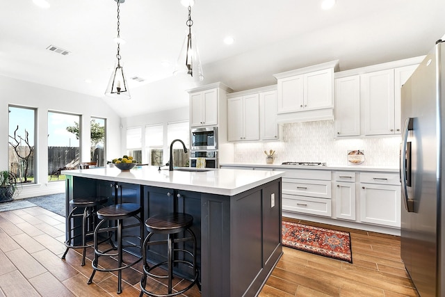 kitchen with stainless steel appliances, light wood-style flooring, backsplash, light countertops, and white cabinets