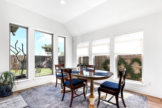dining area featuring vaulted ceiling, wood finished floors, and baseboards