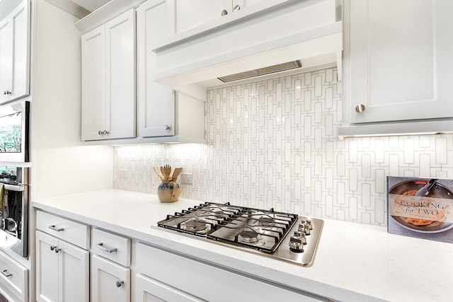 kitchen with exhaust hood, tasteful backsplash, light countertops, white cabinets, and appliances with stainless steel finishes