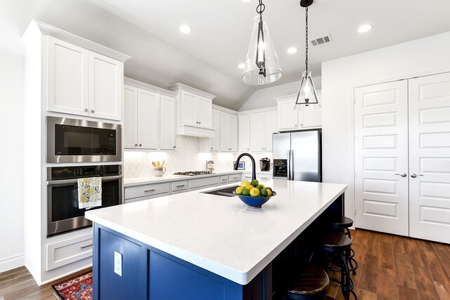 kitchen featuring a kitchen island with sink, stainless steel appliances, light countertops, and a sink