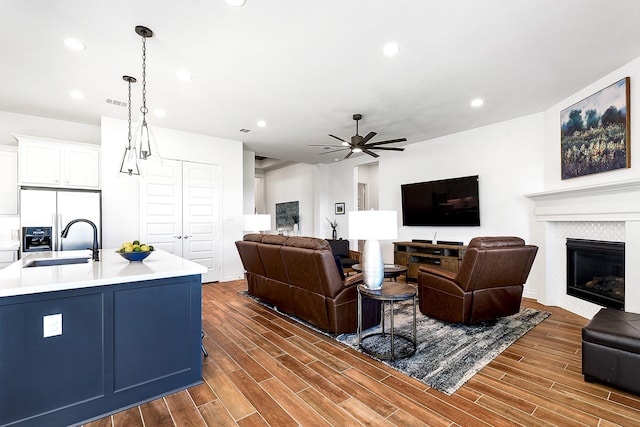 living area with a tiled fireplace, recessed lighting, ceiling fan, and dark wood-style flooring