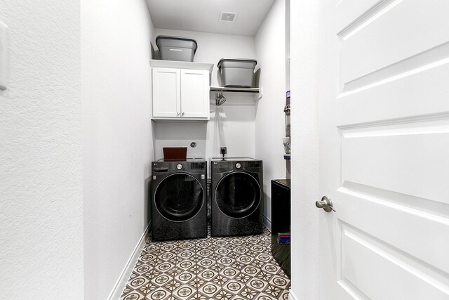 laundry area with baseboards, visible vents, cabinet space, and washing machine and clothes dryer