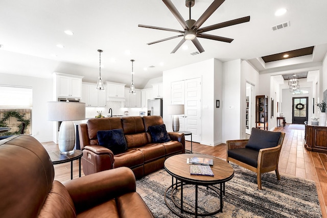 living area featuring visible vents, ceiling fan, light wood-type flooring, and baseboards