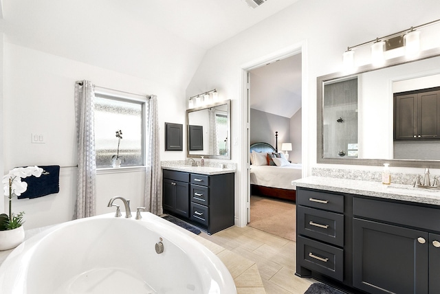 ensuite bathroom featuring a tub, a healthy amount of sunlight, and lofted ceiling